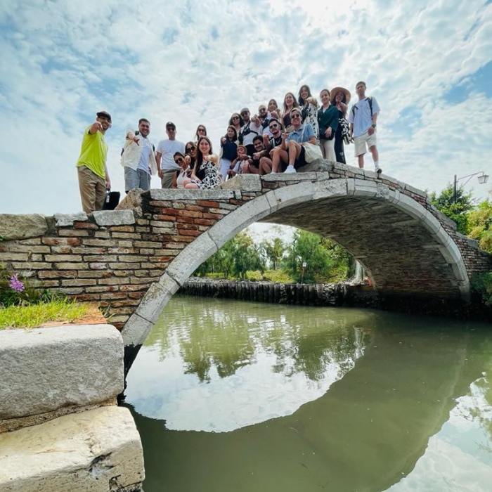 Students on top of a bridge with green shining water below.
